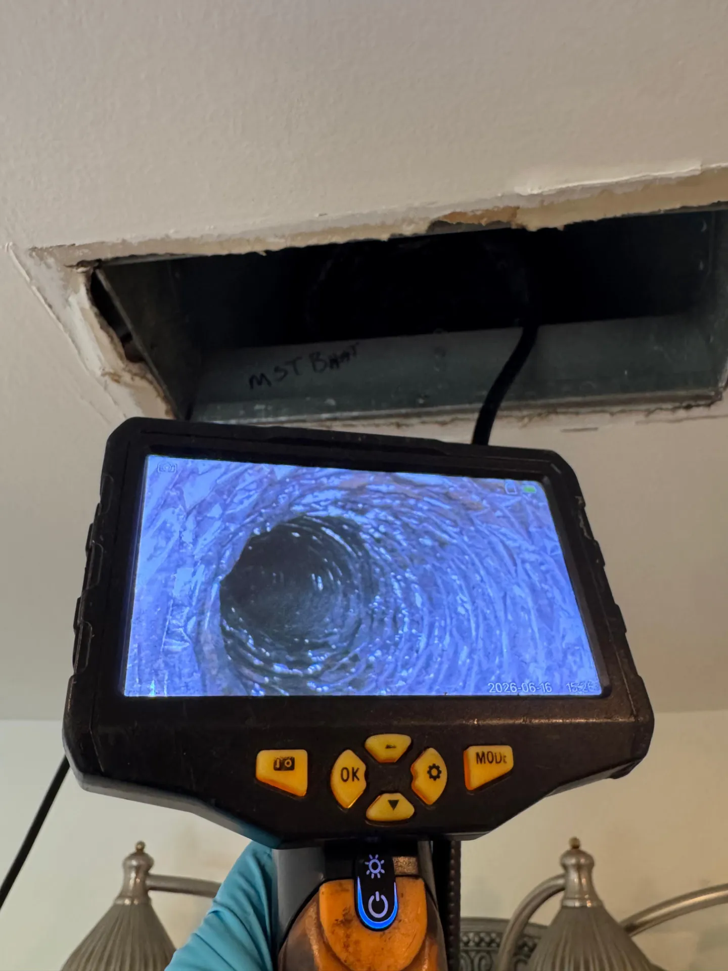 Inspection camera monitor showing a duct interior below an open ceiling register