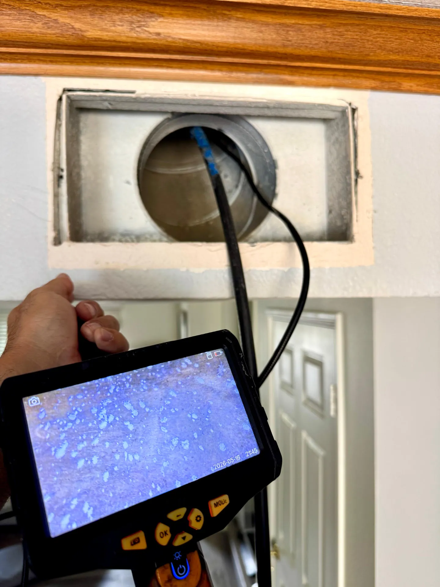 Inspection camera cable inserted into a wall duct opening with the monitor in hand