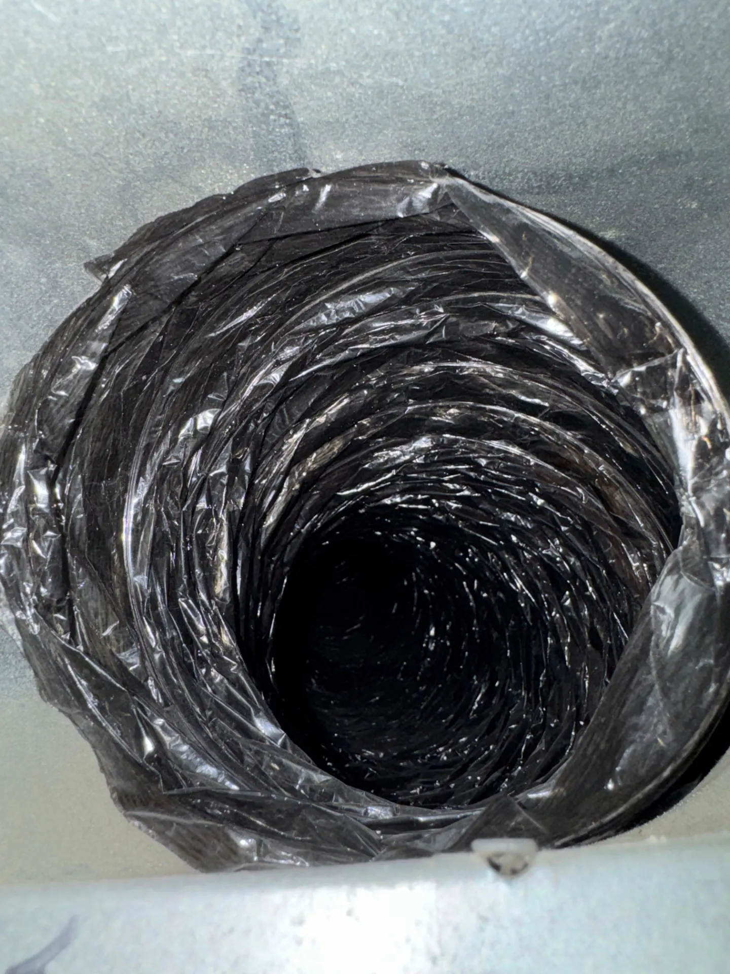 Close-up looking into a black flexible duct from its opening