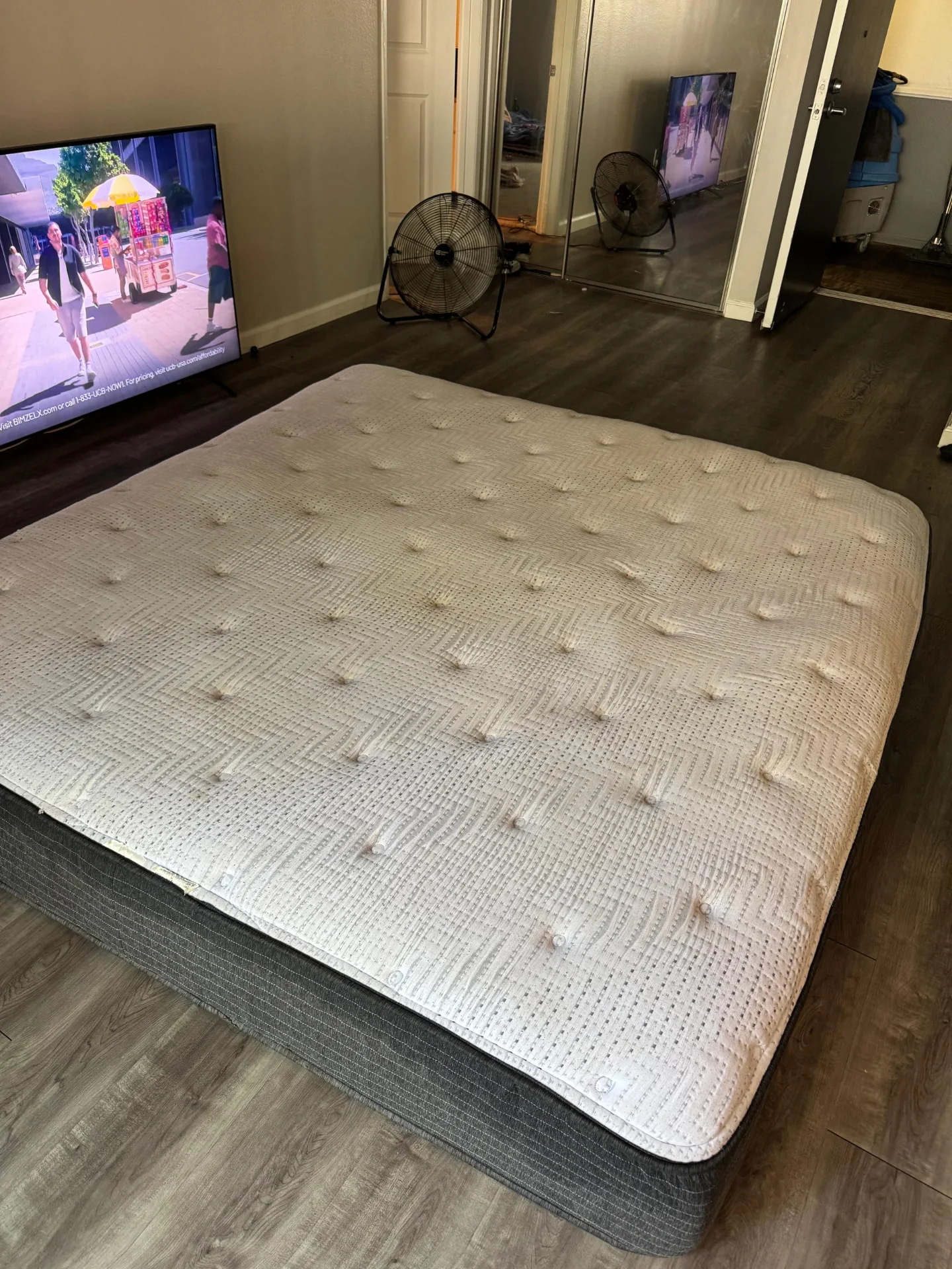 Uncovered quilted mattress in a living room beside a television