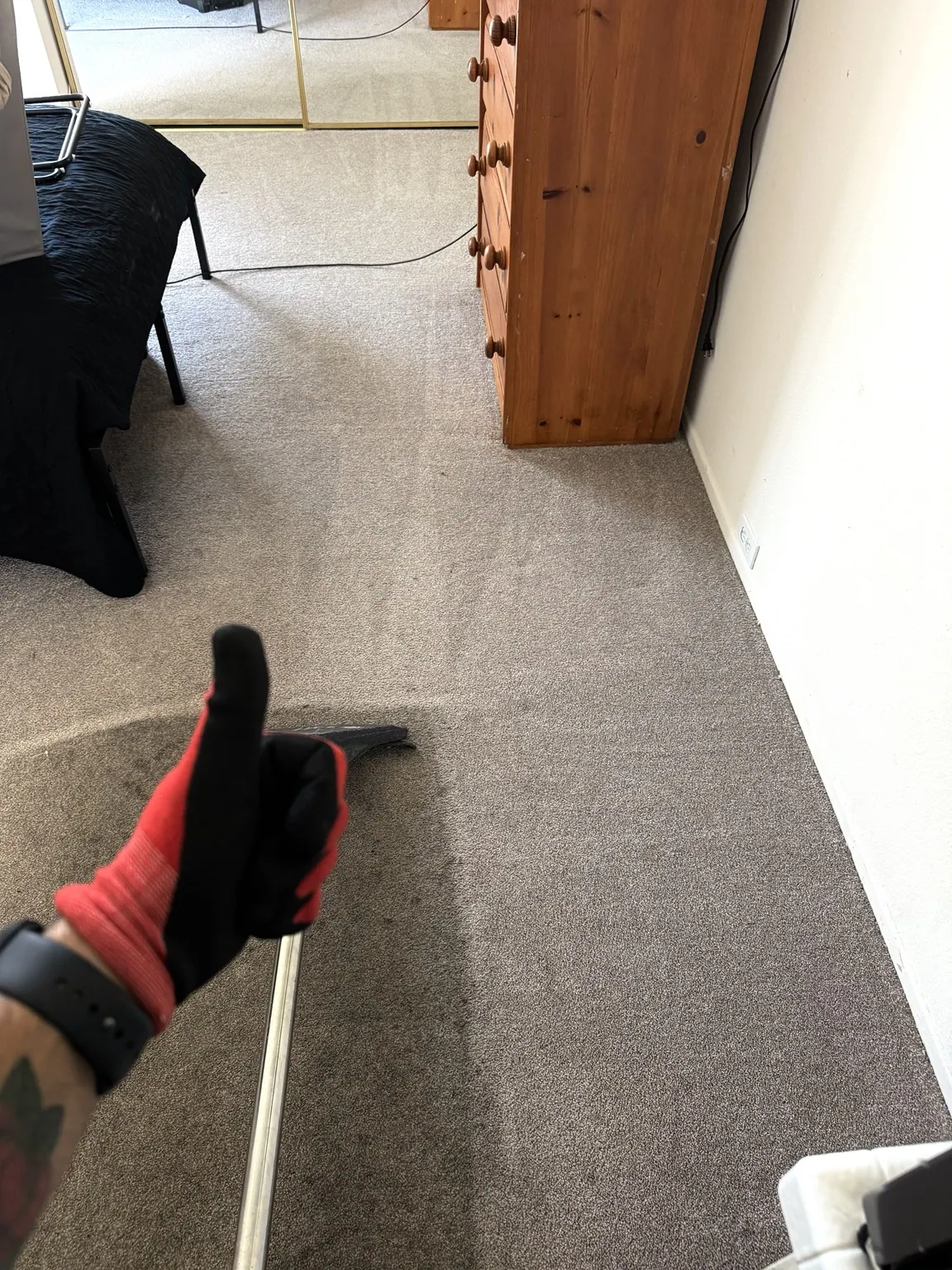 Technician working a cleaning wand across bedroom carpet