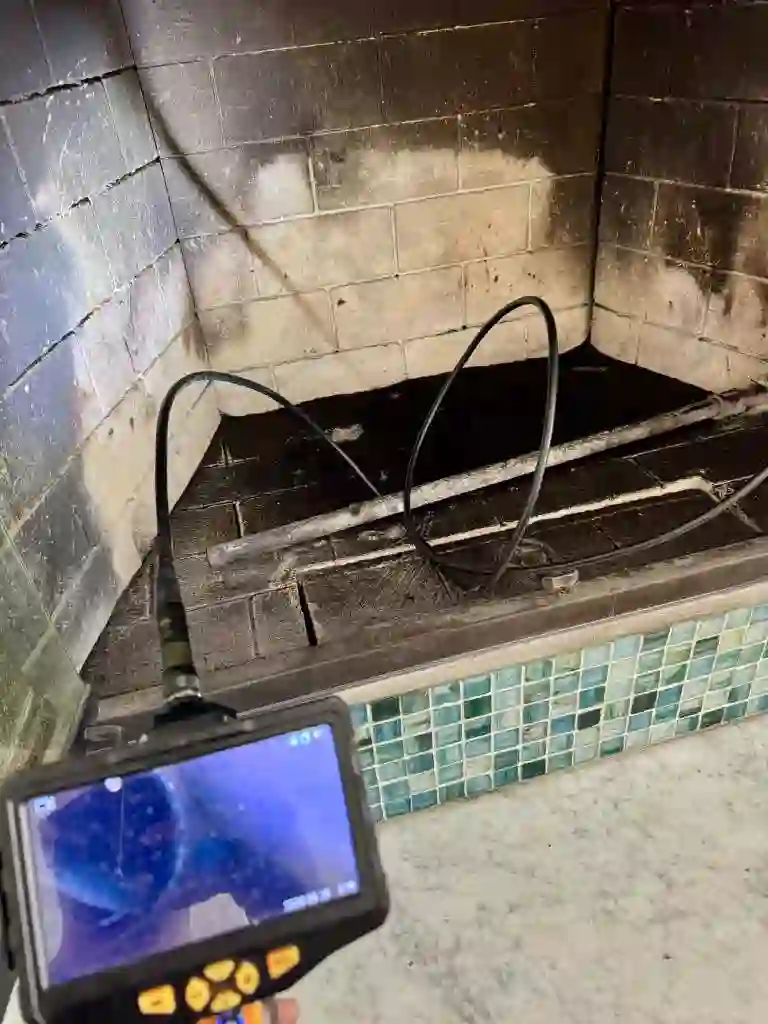 Chimney inspection camera and monitor inside a soot-coated fireplace