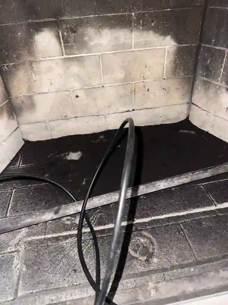 Soot-covered firebox walls and floor with the inspection camera cable in place