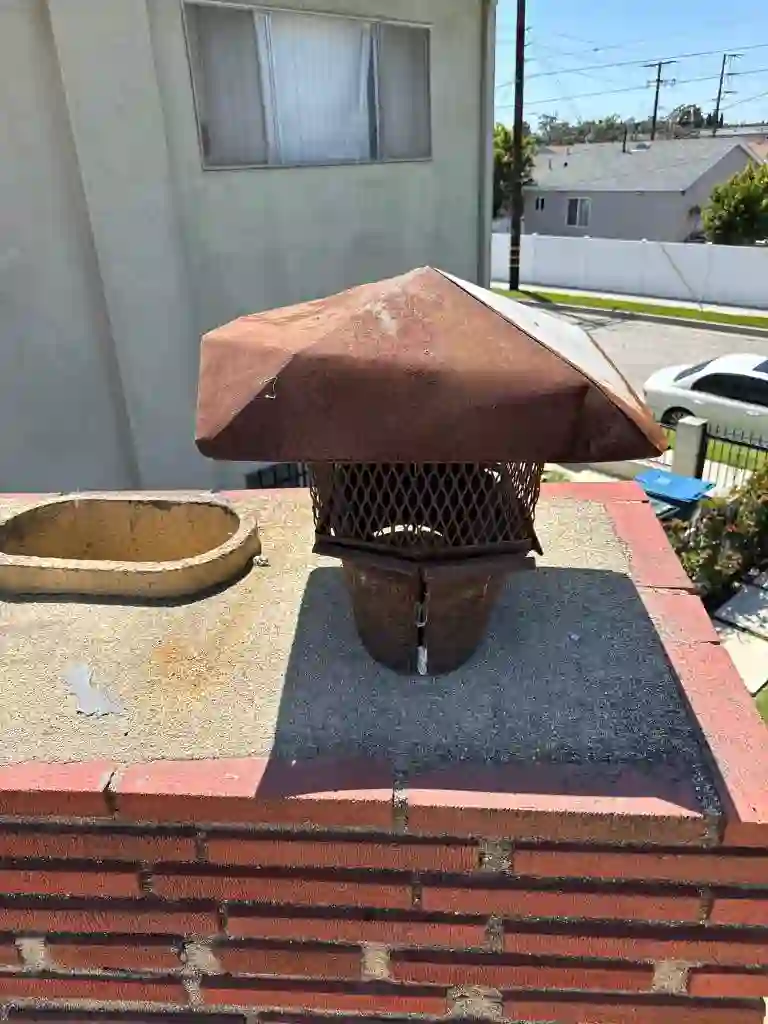 Rusted chimney cap on a brick chimney crown before replacement